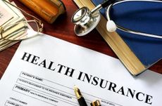 Private health insurance on a wooden surface with glasses.
